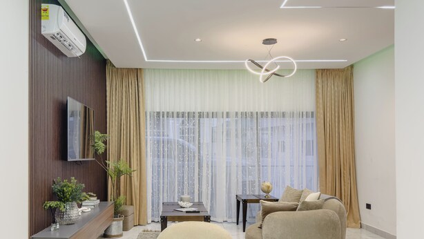 Una sala moderna con un sofá, una mesa de comedor y un televisor en la pared.