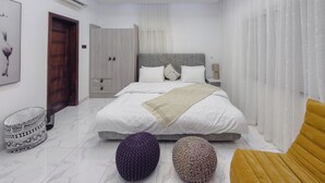 Un dormitorio moderno con una cama grande, mesitas de noche, un armario y una silla.