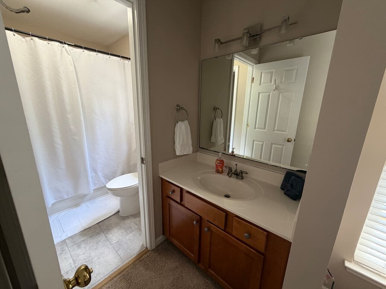 A bathroom with a toilet, sink, mirror, and shower curtain.