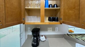 Een keuken met houten kastjes, een koffiezetapparaat en divers keukengerei.