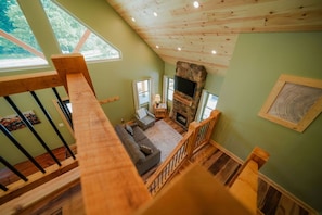 A loft-style living area with a stone fireplace, a sofa, and a television.