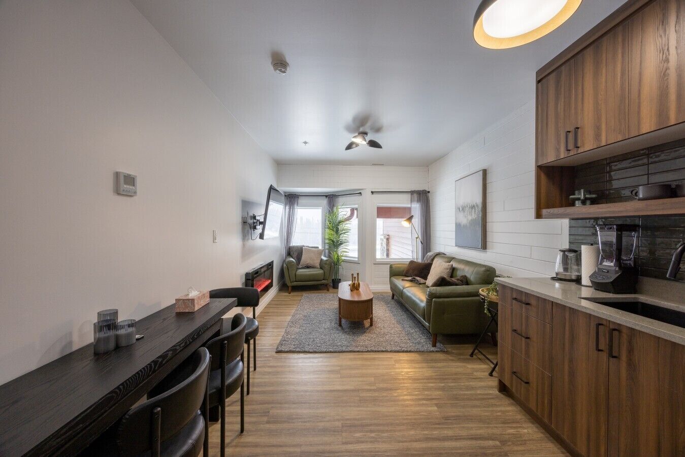 A compact living space with a kitchenette, a dining area, and a seating area with a sofa and a coffee table.