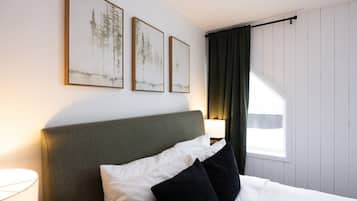 Una habitación de hotel con una cama, una mesita de noche con una lámpara y tres cuadros en la pared.
