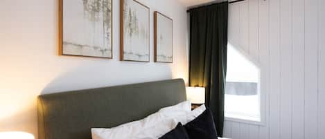 Una habitación de hotel con una cama, una mesita de noche con una lámpara y tres cuadros en la pared.