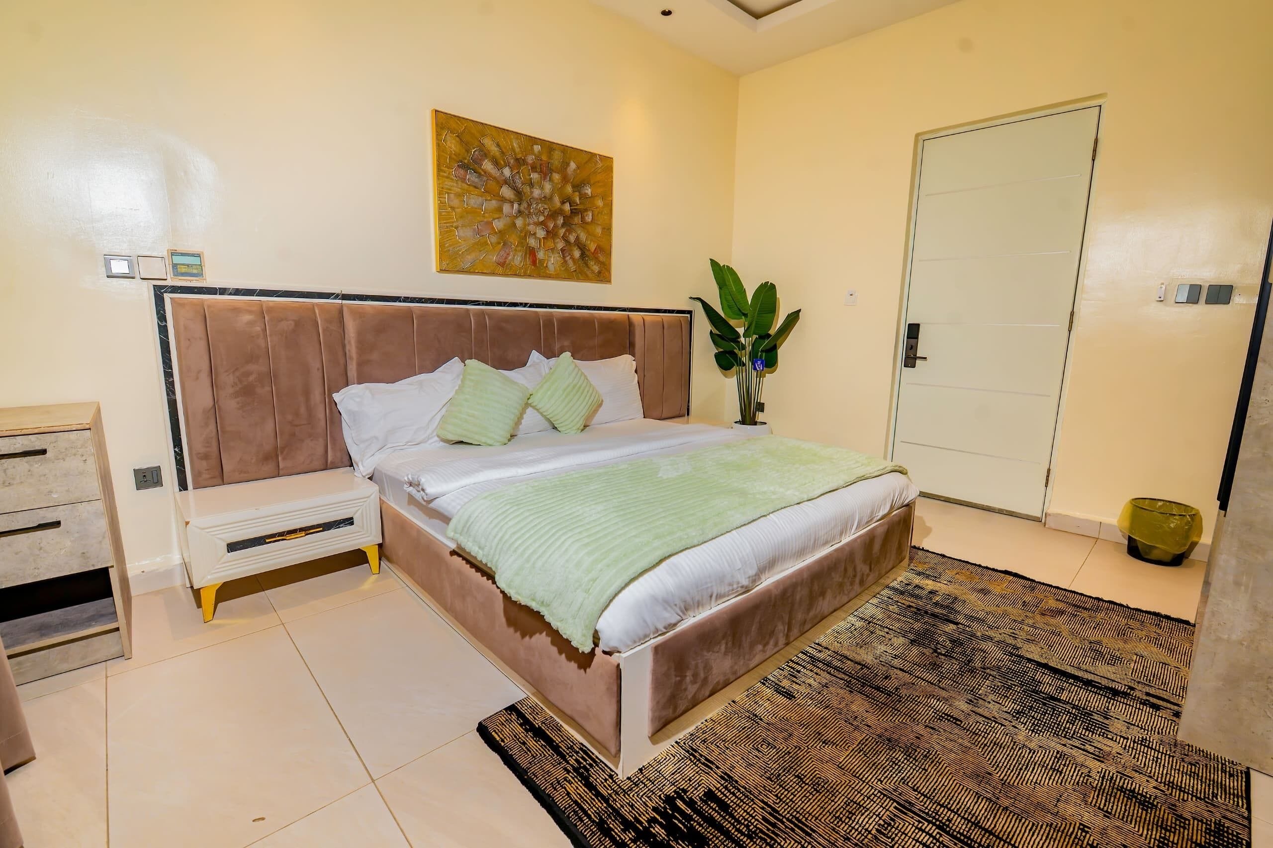 Una camera da letto con un letto, comodino, quadri alle pareti e una porta.