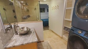 Ein kleines Badezimmer mit Waschbecken, Spiegel und Waschmaschine.