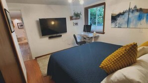Ein Schlafzimmer mit einem Bett, einem Schreibtisch, einem Stuhl, einem Fernseher und einem Fenster.