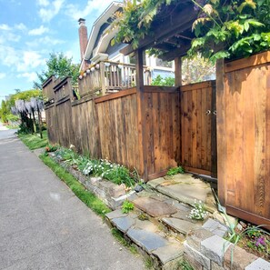 A wooden fence with a stone pathway leading to a house. - The Holdfast: Rare 3-Bedroom Garden Retreat Near Old Ballard (Seattle)