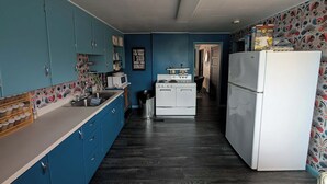 A kitchen with blue cabinets, a white refrigerator, a stove, and a microwave.
