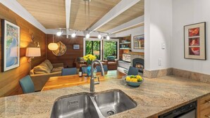 Una cocina moderna con encimera de granito, pileta doble y comedor con mesa y sillas de madera.