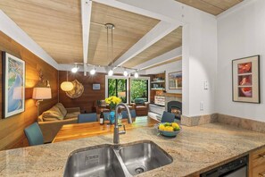 A modern kitchen with a granite countertop, a double sink, and a dining area with a wooden table and chairs. - Beautiful Sun Valley Condo - 2 bedrooms + loft (Sun Valley)