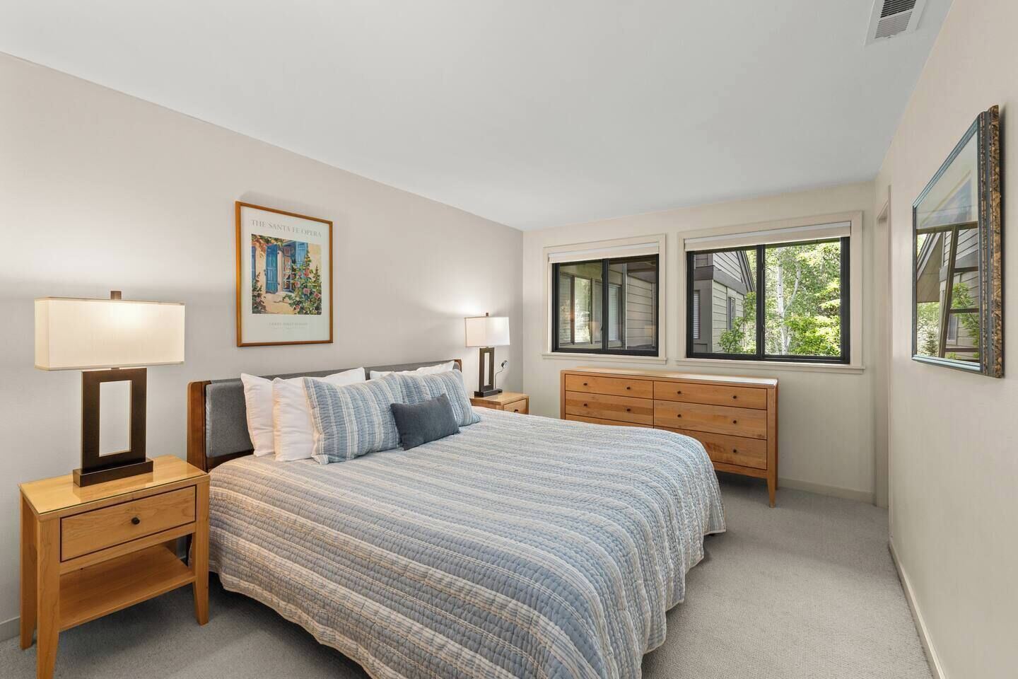 Quarto com cama, mesas de cabeceira, cômoda e janela com vista.