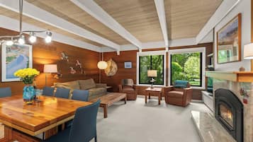 Una sala de estar moderna con techo de madera, chimenea, comedor y ventanas amplias.