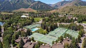Zona residencial con varias canchas de tenis, piscina y casas rodeadas de montañas.