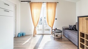 Una sala de estar moderna con un sofá, una mesita redonda y un ventanal corredizo con cortinas.