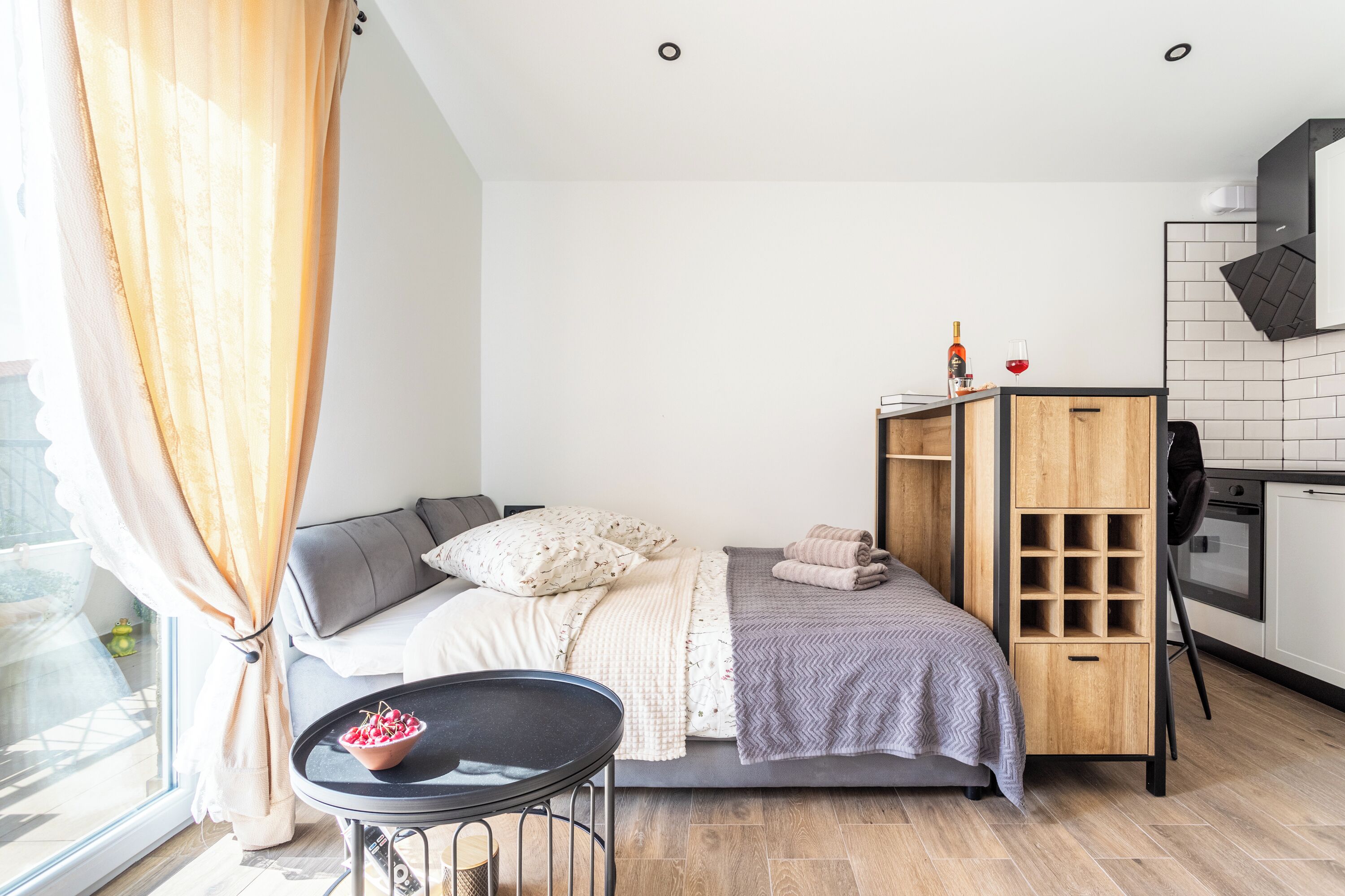 A modern bedroom with a bed, bedside table, and a small kitchenette.