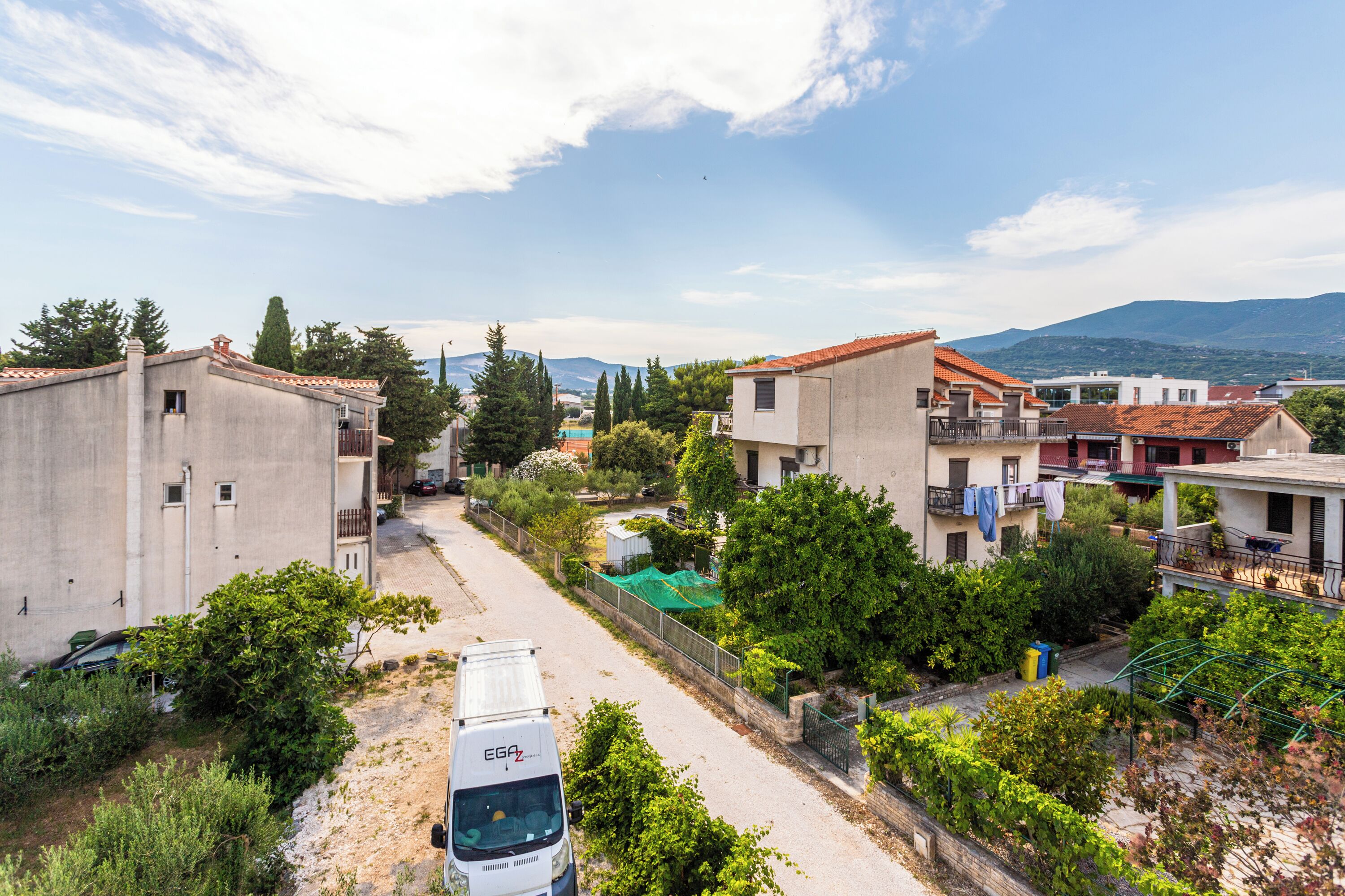 Un quartier résidentiel avec des maisons, un fourgon et un ciel dégagé.