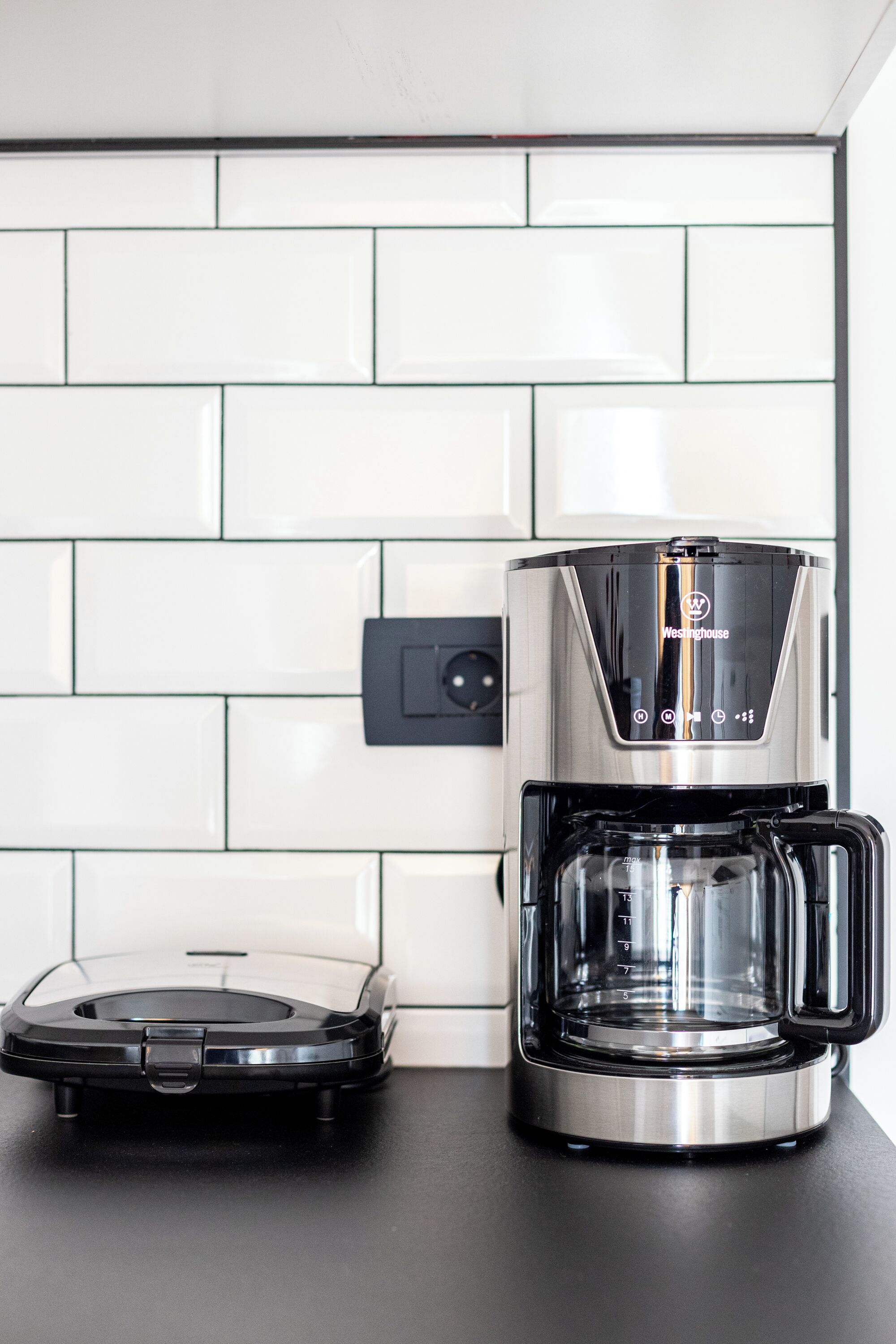 A kitchen with a coffee maker and a robotic vacuum cleaner.