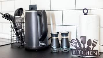 A kitchen counter with a kettle, salt and pepper shakers, a whisk, and a spatula on a tray.