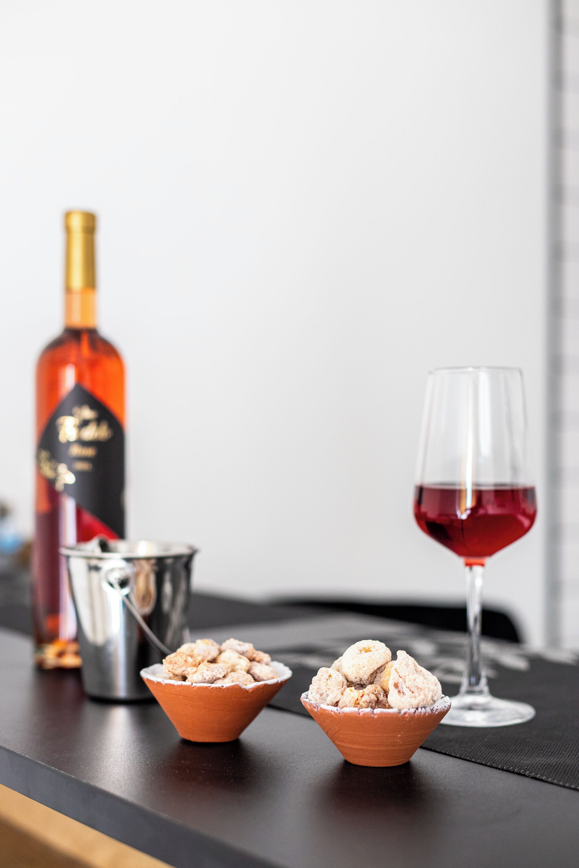 A table with a bottle, a glass, and two bowls of ice cream.