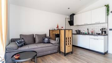A modern living space with a sofa, coffee table, and kitchen area.