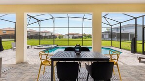 A covered patio with a pool, outdoor seating, and a view of residential buildings. - 8904-TropicalHaven (Kissimmee)