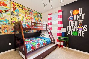 Ein Schlafraum mit Etagenbett, einer Wandmalerei mit Comic-Motiven und einem motivierenden Zitat sowie einem kleinen, grünen Beistelltisch.