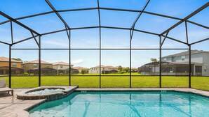 A swimming pool with a hot tub, surrounded by a covered area with a view of houses. - 8904-TropicalHaven (Kissimmee)