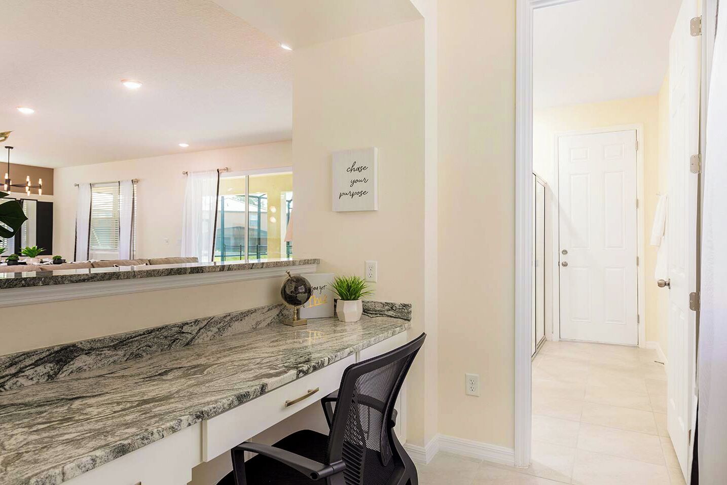 A modern kitchen with a marble countertop, a black chair, and a wall-mounted mirror.