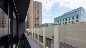 Un pasillo estrecho con vistas a edificios altos, un edificio azul con ventanas y un edificio beige con rejillas.