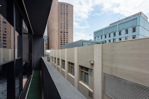 A narrow corridor with a view of tall buildings, a blue building with windows, and a beige building with vents. - Stylish 3BDR Unit in the Heart of Melbourne CBD (Melbourne)