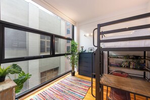 A compact room with a bunk bed, a small desk, a bookshelf, and a potted plant. - Stylish 3BDR Unit in the Heart of Melbourne CBD (Melbourne)
