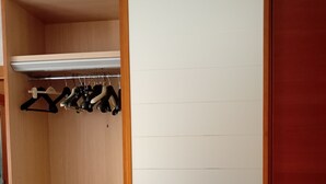 Un armari ampli amb portes de fusta, una barra penjant i calaixos.