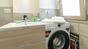 Un bany modern amb un lavabo, un mirall i una rentadora.