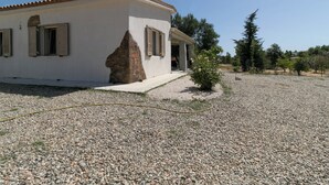 Una casa amb un element de pedra, un camí de grava i un petit arbust.