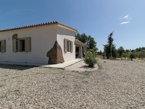 A house with a stone feature, a gravel driveway, and a small bush. - Villa Su Entu | with Garden close to the beach (Lanusei)