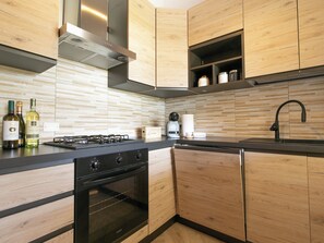 Een moderne keuken met houten kastjes, een gasfornuis, een inbouwoven en een zwart aanrecht.