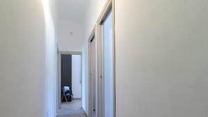 Passadís estret amb terres de fusta, parets blanques i una porta que dona a una altra habitació.