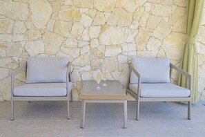 Deux chaises de couleur gris clair avec des coussins, une petite table carrée et deux flûtes à champagne posées sur la table.