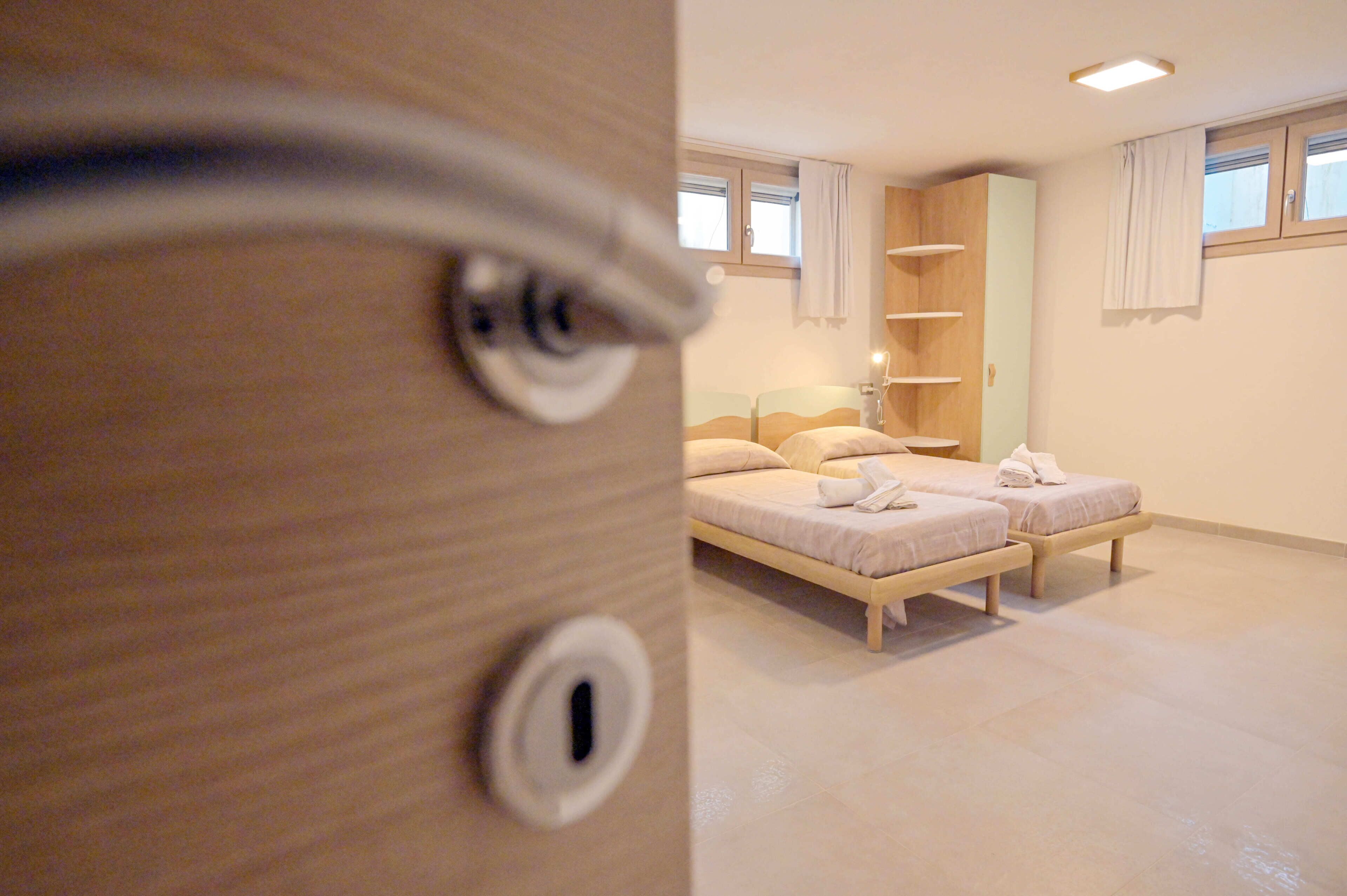 Una camera da letto con due letti, un'armadio in legno e una finestra con tende.