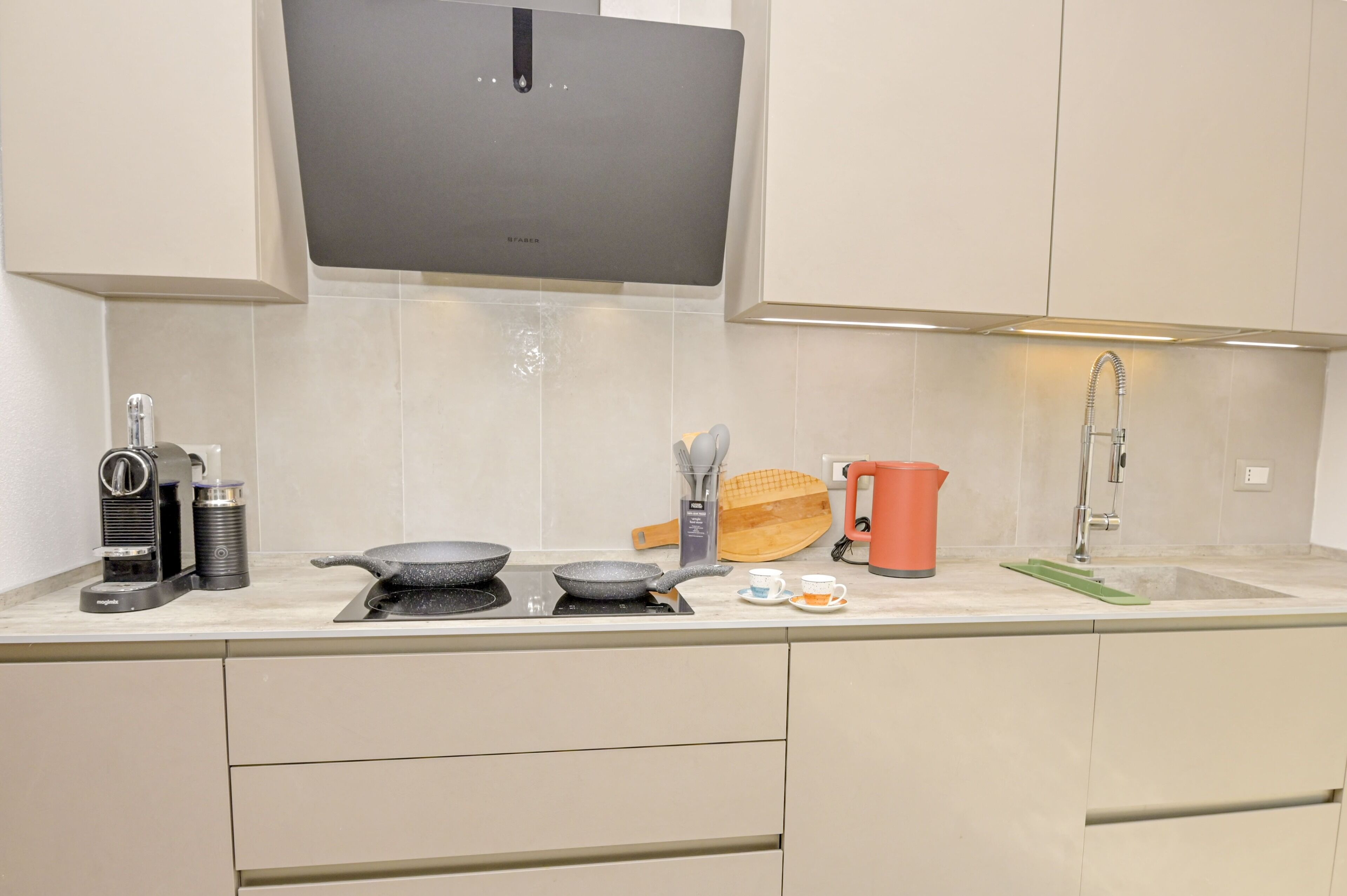 Une cuisine moderne équipée d’une cuisinière intégrée, d’une machine à café, d’une bouilloire et d’un évier.