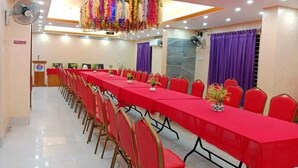 A conference room with a long table, red chairs, and ceiling fans.