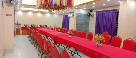 A conference room with a long table, red chairs, and ceiling fans.