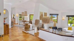 A spacious living area with a dining table, chairs, and a sofa. - Villa Arasu - Private, gated estate 100 meters from the beach - Punta d'Araso (Zonza)