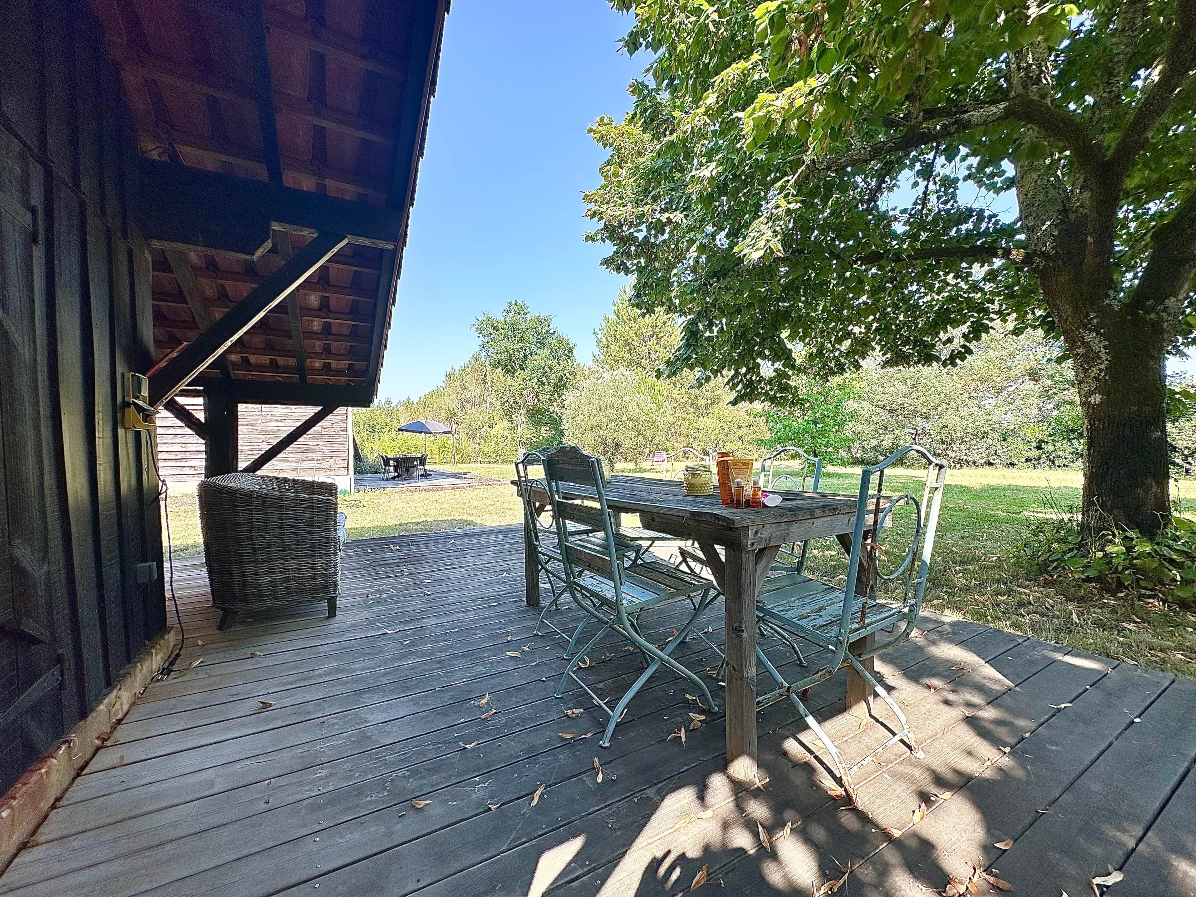 A wooden deck with a table and chairs, a wicker basket, and a trash can.