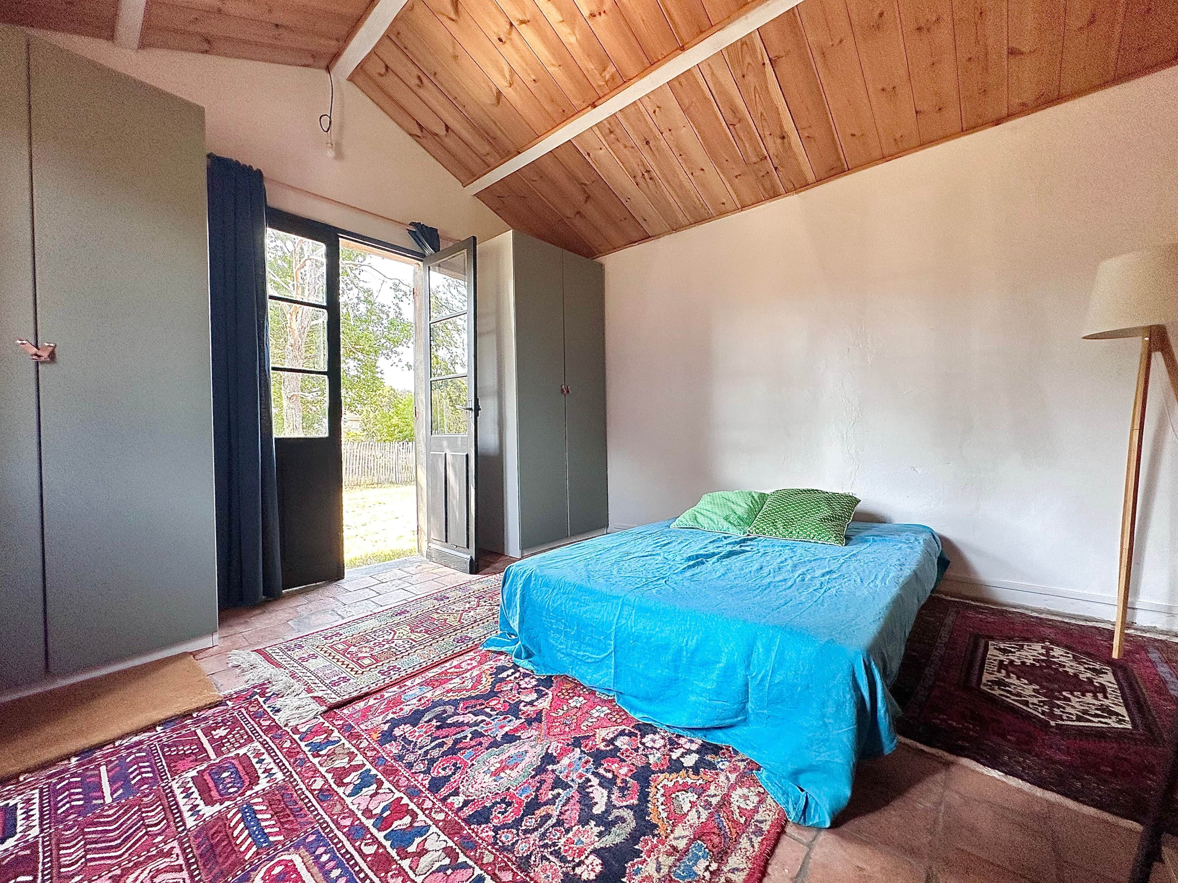 Ein Schlafzimmer mit einem Bett, einer Tür, einem Fenster und einem Deckenventilator.