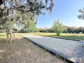 Ein Garten mit Holzbank, Kiesweg und Bäumen.