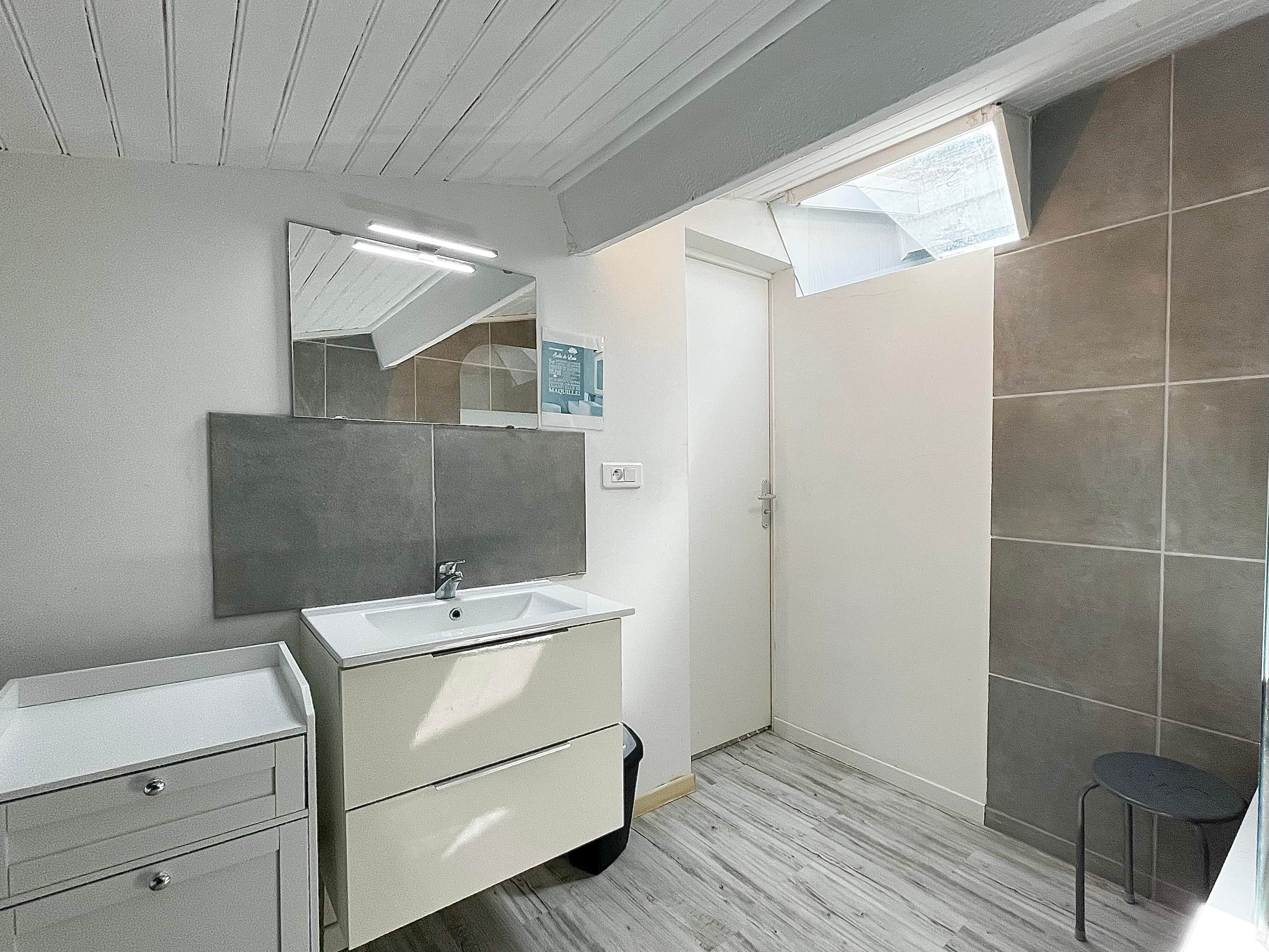 A modern bathroom with a vanity, mirror, and tiled walls.