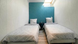 A small, narrow room with two single beds, a small table, and a skylight. - RIVÉA - 2-bedroom apartment near the ocean (Mimizan)