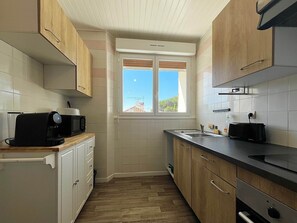 Eine kleine Küche mit Holzausstattung, einer Mikrowelle, einem Toaster und einem Fenster mit Blick zum Himmel.